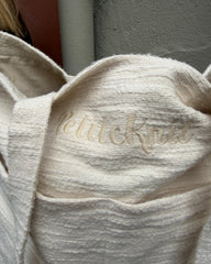 Knitter's Shopper Light i farven Cloud stående på bænk med fokus på det broderede logo