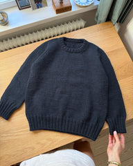 Blå Niels Sweater Junior liggende på skrivebord
