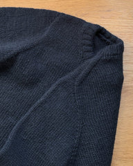 Blå Niels Sweater Junior liggende på skrivebord med fokus på den eropæiske skulderkonstruktion