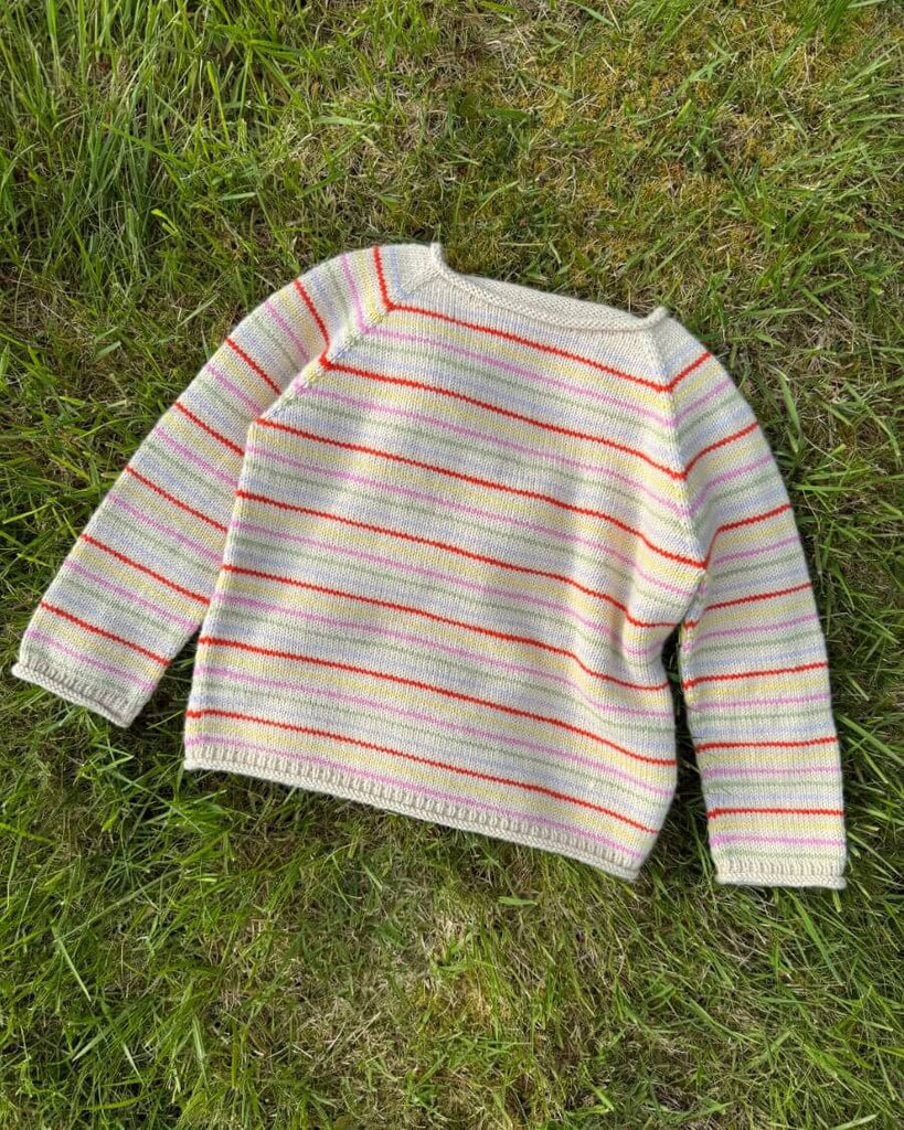Mangefarvet Frankie Sweater Junior liggende på græs