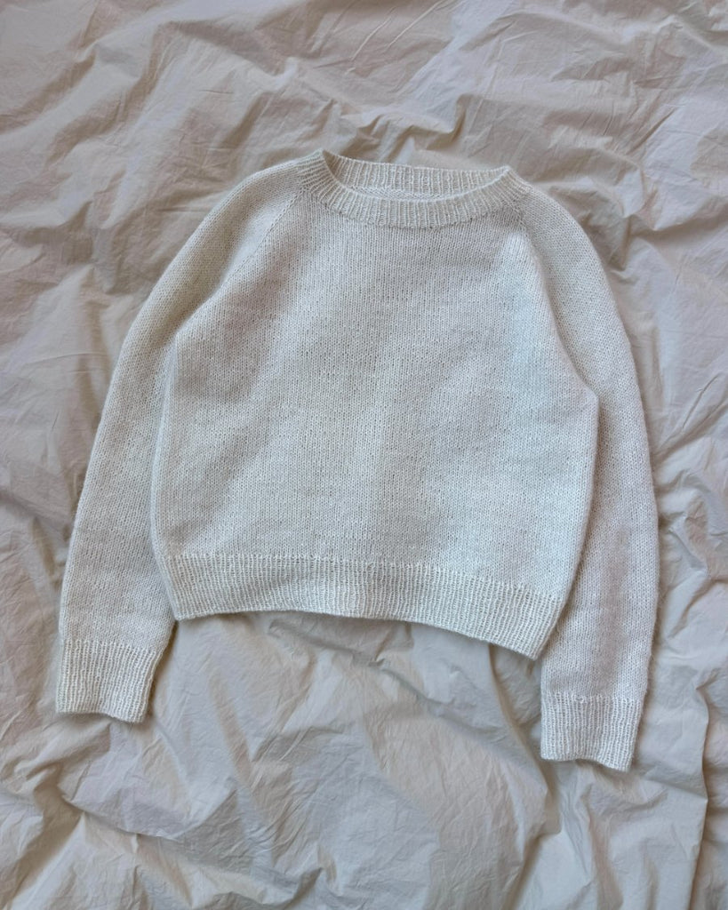 Hvid Ingen Dikkedarer Sweater liggende på sengetøj