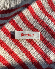 Petiteknit label med rød skrift 