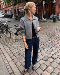 Kvinde iført lysegrå Petra Jacket med kaffe i hånden