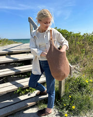 Kvinde med lysebrun terrazzo bag på strand