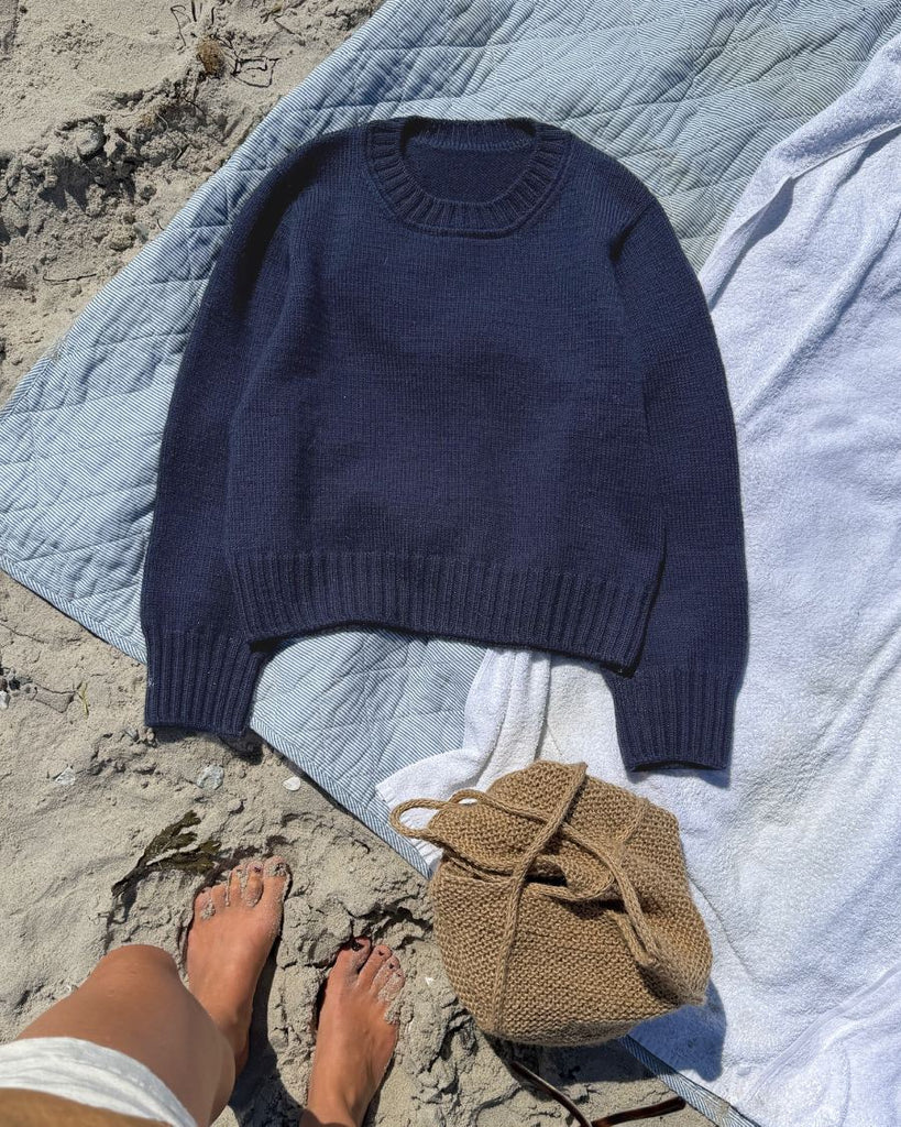 Blå Vega Sweater på strandtæppe
