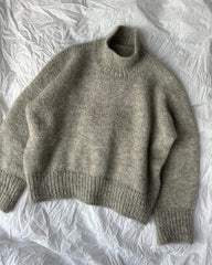 Lysegrå Weekend Sweater liggende på dyne