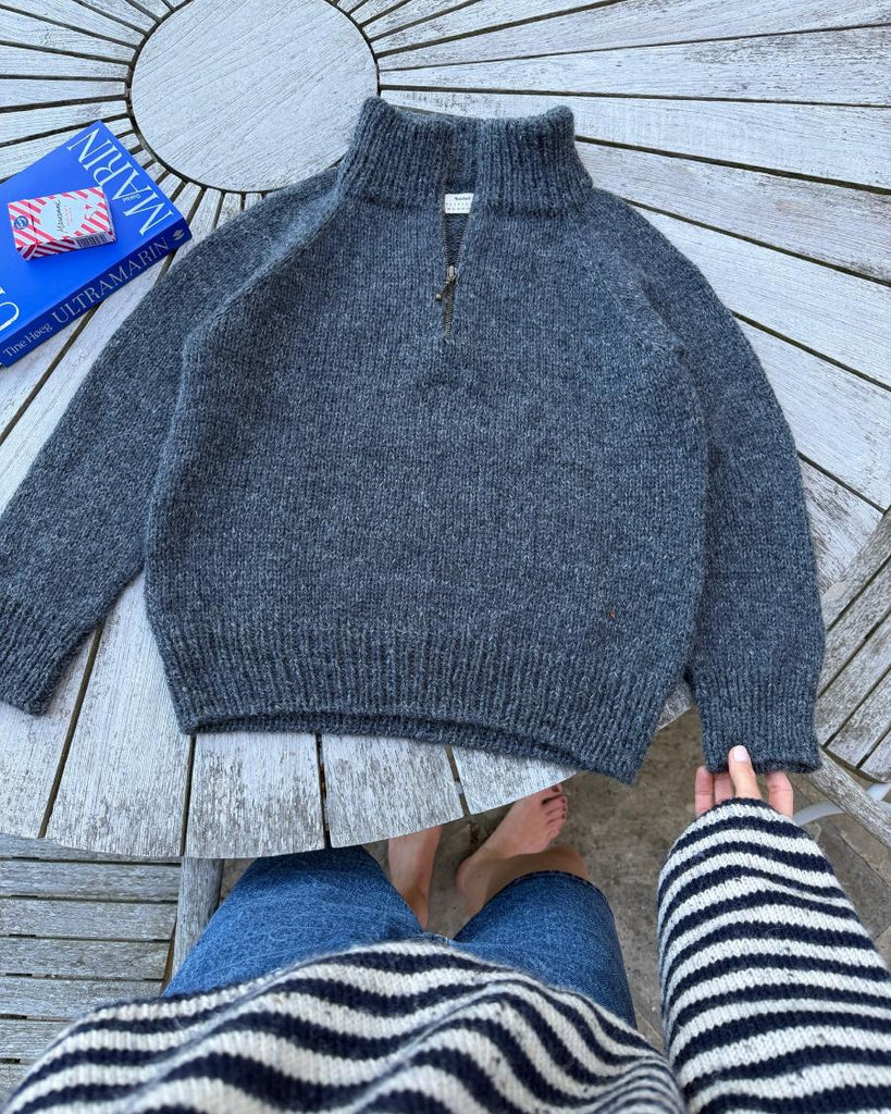 Møkegrå Zipper Sweater Junior liggende på havebord