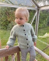 Barn iført lysegrøn Novice Cardigan Mini – Chunky Edition
